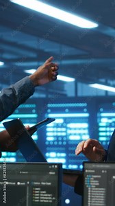 Vertical video Coworking system administrators in server hub monitoring data center energy consumption across hardware using tablet. Colleagues inspecting supercomputers, ensuring malfunctions are