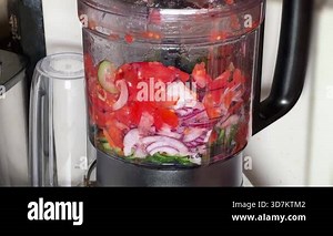 Slicing different fresh vegetables in bowl of electric food processor