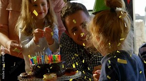 Confetti animation over children celebrating birthday with cake and candles