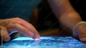 Man looking for a spot on 3D Earth map using WiFi at night. Guy exploring travel destination online. Modern tech device screen. Closeup male fingers searching place on satellite view map using tablet