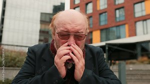 In a 4k video, an elderly man faces the trials of the flu season, manifesting persistent sneezing and coughing, offering a poignant view of healthcare challenges in the aging population.
