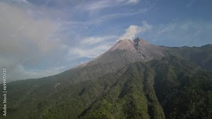 4k Video Footage of aerial view of Merapi Volcano mountain during eruption in the morning with forest and hills below in Cangkringan, Sleman, Yogyakarta, Indonesia. Concept for geology.