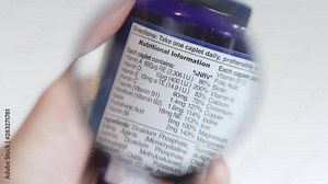 Examining nutritional information label on a bottle of supplements with a magnifying glass, coming slowly into focus