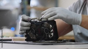 Computer upgrade and diagnosing breakdowns. Repairman installing ventilator CPU on graphics card for cooling, hands closeup. He screws fan to chipset. PC repair and maintenance service in workshop.