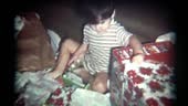 A young boy opens Christmas presents. Vintage 1970s film transfer.