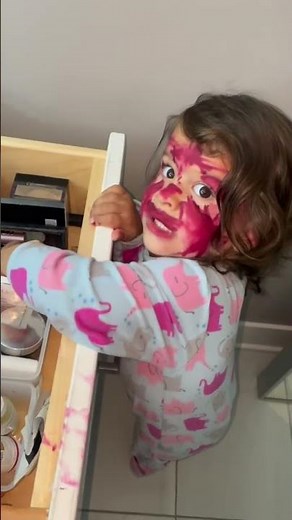 Little girl paints her face with lipstick in Prairie Village, Kansas, USA