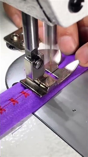 stitching red cross patterns on purple fabric with a sewing machine to create decorative designs
