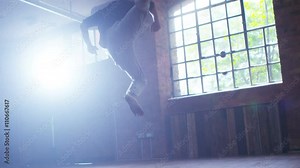 Asian martial artist training alone, practising moves in industrial building