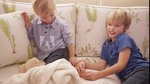 Young blond boy tickling his brother's feet on a sofa