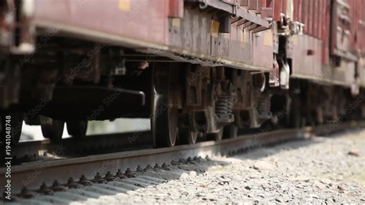 Cinematic close up of freight train wheels rolling on railway tracks, highlighting heavy transportation, industrial logistics and ground cargo movement within rail infrastructure systems.
