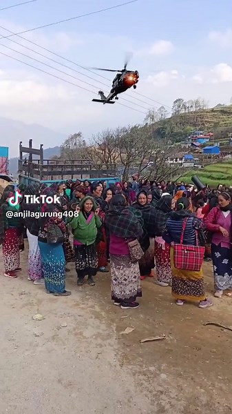 Women in Traditional Attire Watching Helicopter