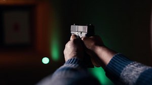 Firing range customer doing shooting activity with pistol, checking if he shot bullseye. Close up of person in shooting gallery learning how to use firearm, analyzing targets shot, camera B