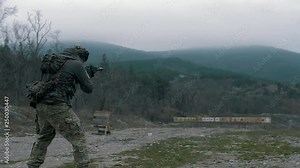 A group of military men in camouflage uniforms are conducting tactical shooting from military weapons on a training dash at targets.