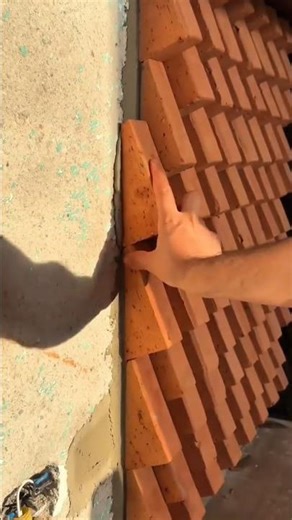 installing orange triangle bricks manually on the wall for a modern textured design