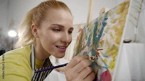Closeup view of inspired woman artist drawing picture by oil dyes in workshop. Pretty young lady student of art school creating masterpiece for exhibition, talent and inspiration, hobby and passion