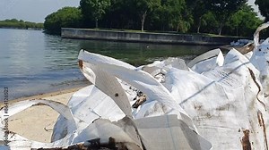 Tilt video of big bags containing oil soaked sand on Lazarus Island, Singapore. Footage shows many bags lining the shore