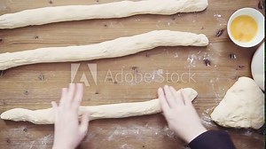 Step by step. Slicing freshly baked challah bread with sesame and poppy seeds.