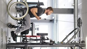 Disabled athlete in wheelchair trains arm muscles in gym, people with disabilities do sports