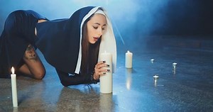 Attractive sexual nun sneaks up to a candle and blows out a candle in a dark smoky studio