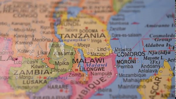 Man Marking Malawi Location with Red Pin on Paper World Map in 4K 60fps Close-Up Travel Concept