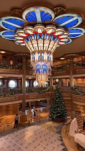 It is chandelier cleaning day in the atrium on the Disney Dream. The ship was docked at Disney Castaway Cay and it was windy! You can see the chandelier swaying as it was lowered. There was more confetti than usual stuck in the chandelier so it was a sight to see as it all flew out. The Dream’s iconic Art Deco chandelier (23 feet wide, 13 feet tall, 24k gold-plated, and sparkling with Swarovski crystals) gets its royal treatment about once a month, usually while guests are off enjoying their own