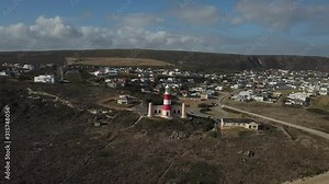 4K sunny summer aerial drone video of Cape Agulhas Lighthouse on southernmost tip of African continent peninsula near Indian Ocean coastal village L'Agulhas, Garden Route, Western Cape, South Africa