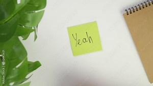 YEAH. congratulations Top view write with a pen on a sticker. Put a colored piece of paper on your office desk and write a note with a black marker.