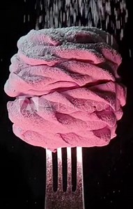 Marshmallows on a fork with falling powdered sugar.