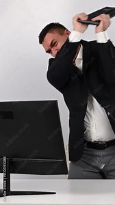 The man gets angry and smashes the keyboard on the monitor. An office worker in a rage breaks the computer. Slow motion. Vertical video.