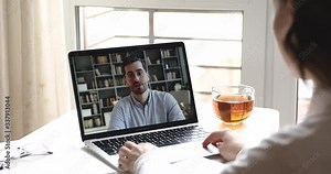 Male distance teacher manager communicate with female student, remote worker by webcam video call. Distant job interview, home office work conference chat, elearning. Over shoulder laptop screen view