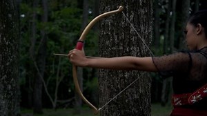 Download Asian Women ready to shoot an arrow from the bow while standing bravely for free