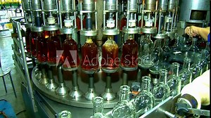 Whiskey and brandy production line. Factory machine pouring alcohol into bottles