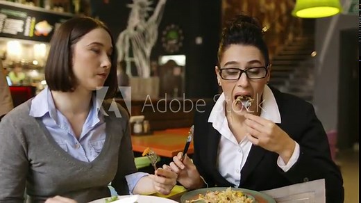 Woman eating salad in an indoor cafe, close up on a plate.