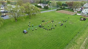 A drone view of amish farmlands and homesteads and approaching amish teens playing volleyball on a sunny day Premium Stock Video Footage