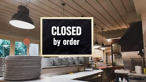 Closed by order sign swinging on empty restaurant pizza kitchen worktop, commercial crisis concept