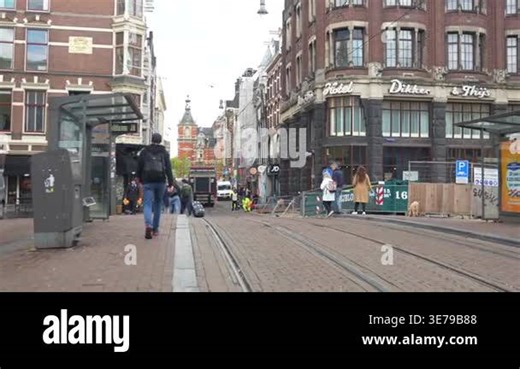 People walk along tram tracks near historic buildings Amsterdam Netherlands April 22 2024 Stock Video Footage - Alamy