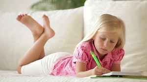 clip-4647185-cute-little-girl-lying-on-sofa-writing