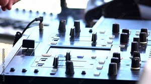 DJ hands touch buttons and sliders on sound mixing controller deck with laptops, monitors and wires, close-up. Disc jockey mix tracks, play electronic music on pro audio equipment in beach club.