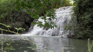 Beautiful cascade waterfall scenery. Water cascades on rock at different levels creating nice flow with white foam. Vegetation around. Serene water below. River course setting.