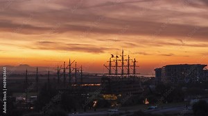 Time-Lapse of Sunrise at the Sea in a Port with Sailing Ships. The Sun Rises Behind the Hills, Painting the Sky in Fiery Bright Colors. Dolly Zoom.