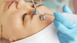Beautician cosmetologist makes a procedure on the face with microcurrent therapy device. Hardware cosmetology in clinic salon for client.