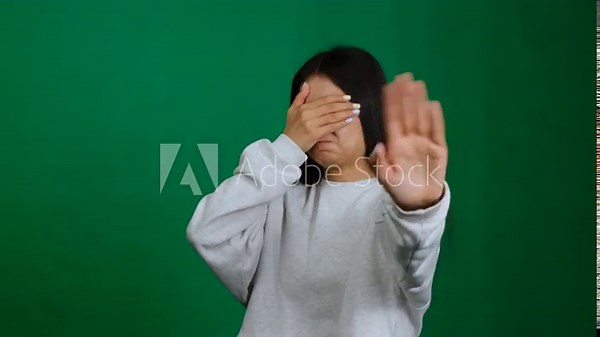 A scared woman covers her eyes, feeling alone and confused. She hides from problems, conveying fear, stress, and depression