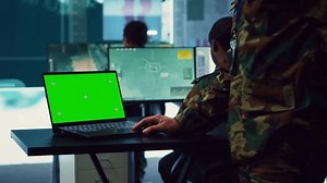Army officer studies isolated greenscreen display on a laptop in control room, military power base personnel monitoring satellite world map for federal operations. Commander in uniform. Camera A.
