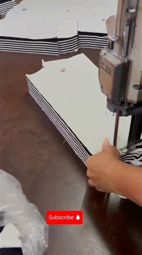 Garment factory worker operating specialized electric knife to precisely shape stacked striped #asmr