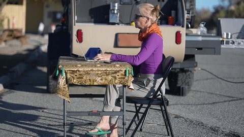 clip-4026458749-mature-woman-sits-table-working-on-computer
