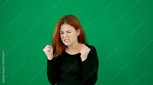 Being angry, clenching your fists, frowning your eyebrows, squeezing your face, nerves, aggression, keeping psychological problems within yourself. middle-aged red-haired woman on a green background