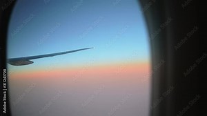 Window seat is the best seat in plane to relax during air travel. Passenger pov through plane window flight during sunset or sunrise above clouds. Close up of porthole of flying airplane at night.