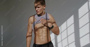 A 23-year-old athletic man trains in a studio, showing off a toned physique with confidence and focus. Athletic Young Man Training in Studio, Flexing Muscles Confidently