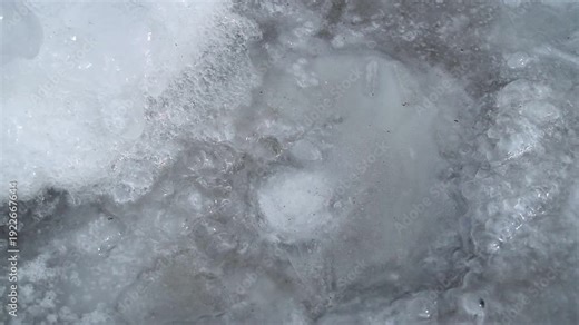 Ice melting on a surface, revealing textures and bubbles in the water, with gradual changes in clarity and detail across the frames