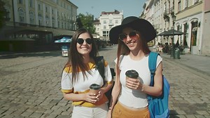 Women drinking coffee walk on European street - Free Stock Video